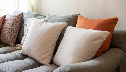 Close-up of a fabric sofa adorned with white and terra cotta pillows in the context of a modern French country home interior design for the living room