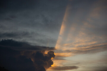 Fototapeta na wymiar golden sun rays on dark cloud and grey sky. natural sun beams in evening.