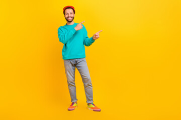 Fototapeta premium Full length photo of positive man dressed turquoise pullover hat indicating at offer empty space isolated on yellow color background