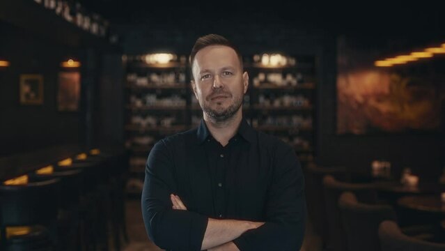 Portrait of an adult man in a dark and stylish bar or restaurant. The owner of the establishment and business is in the picture.