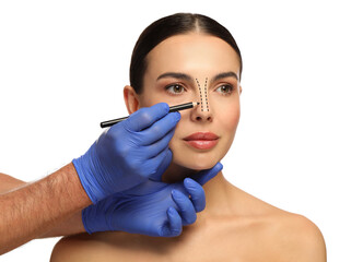 Woman preparing for cosmetic surgery, white background. Doctor drawing markings on her face, closeup