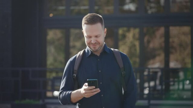 Modern urban man uses a smartphone on a city street. Internet technologies make it easier to access various services and assistants using mobile applications.