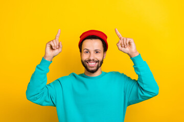 Portrait of cool cheerful man beaming smile indicate fingers up above empty space offer isolated on...