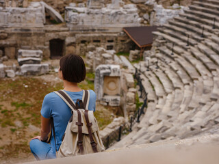 Woman tourist sitting in amphitheater enjoying solitude. travel to ancient city of Side, Antalya...