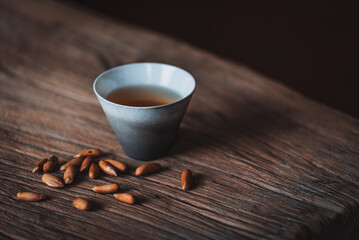 Cup of tea with pine nuts on old wooden background. Selective focus.
