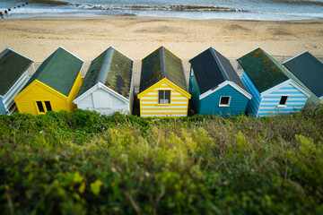 Row of colourful wooden beach huts seen in the popular Suffolk seaside resort of Southwold. The empty beach and North Sea can be seen.