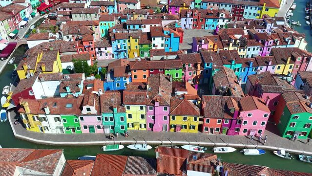 Colourfully painted house facades on Burano island during a sunny summer day. Burano is a small island in the Venetian Lagoon and a popular tourist destination
