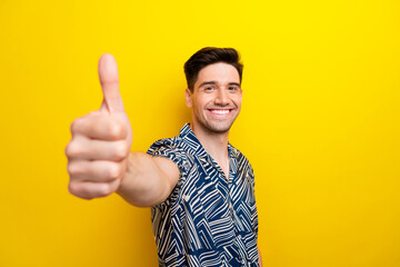 Portrait of toothy beaming satisfied guy with trendy hairstyle wear print shirt show thumb up to...