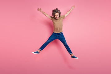 Full length photo of eccentric guy with long haircut wear stylish t-shirt denim pants jumping high isolated on violet color background