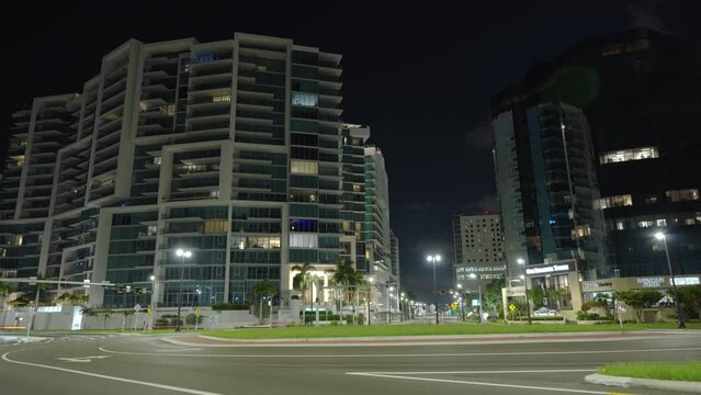 Time-lapse of moving traffic in Sarasota city downtown at night. Skyscraper buildings over urban transportation infrastructure in Florida