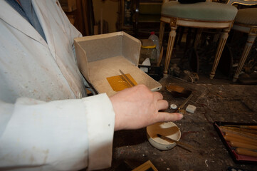 Artigianato, artigiano. Doratore al lavoro con foglia d'oro per restauro doratura.