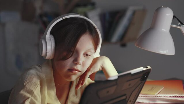Distant School Learning Concept. Girl in Headphones Uses Tablet Computer