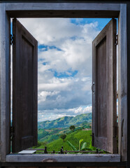 a view trough a wooden window at the green mountains of Doi Chang Mountains of Chiang Rai Northern Thailand, Natural mountain view on Doi Chang, Chiang Rai Province, Thailand