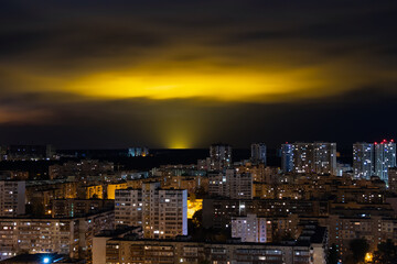 Fototapeta na wymiar Light pollution of nature - glow in night clouds over a city with multi-storey buildings, the problem of urbanization and ecology