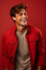 Obraz premium Young handsome caucasian man wearing red jacket, smiling and laughing. Bright red background. Studio photography.