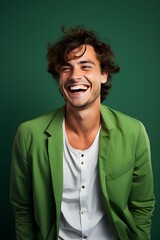 Young handsome caucasian man, smiling and laughing, wearing bright clothes. Bright solid green background. Studio photography.