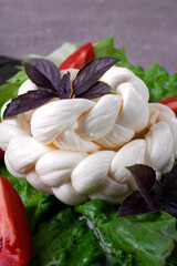 Braided cheese on salad leaves. Chechil or mozzarella. Pasta filata technique used. Close-up
