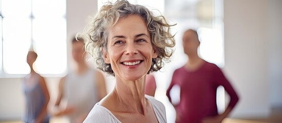 Mature woman happily practicing contemporary dance with others in studio With copyspace for text