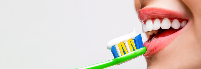 Smiling woman with healthy beautiful teeth holding a toothbrush. Close up of perfect and healthy...