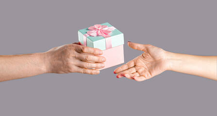 Gift box in hand, surprise and holiday concept. Man hands holding valentines day gift. Male and female hands holding pink gifts box. Girl gives a gift to man