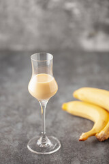 Banana liqueur in grappas glasses and fresh  bananas on the table. Copy space