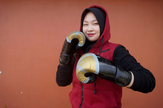 Young Asian Muslim Woman Boxer In Gloves Training On  Red Background