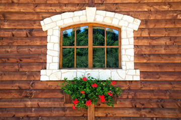 Fototapeta na wymiar Window with flowers on a wooden wall