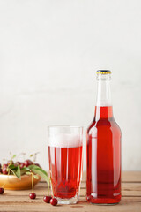 Boozy Refresing Cold Hard Cherry Cider in a Pint Glass and Bottle on wooden table. Copy space