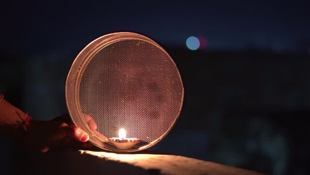Indian married Woman celebrating Karva Chauth festival at night. oja thali for festival of Karwa chauth celebration