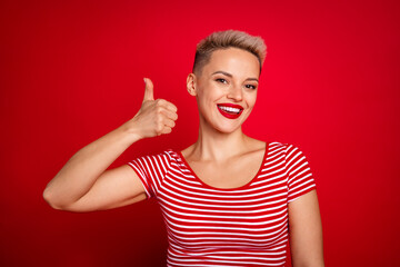Photo of lovely glad girl toothy bright smile wear trendy clothes demonstrate thumb up cool offer isolated on red color background
