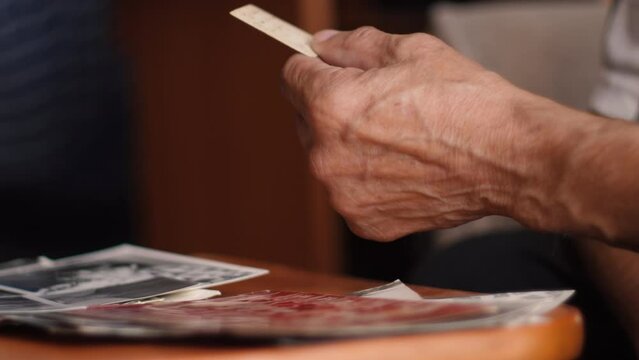 An elderly man looks at old photographs and remembers the past. Black and white photographs that remind you of the past. It used to be better.