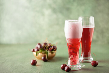 Boozy Refresing Cold Hard Cherry Cider in a Pint Glass and Bottle on wooden table. Copy space