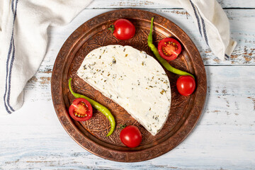 Herb cheese on a copper plate. Slices of herbed cheese on wooden background. local name otlu peynir. Top view