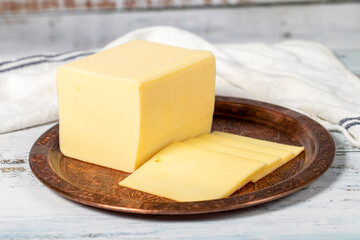 Fresh cheese or kashkaval in a copper plate. Fresh cheddar cheese on wooden background. local name kasar peyniri. Close up