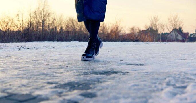 A walking woman slips while stepping on the ice.