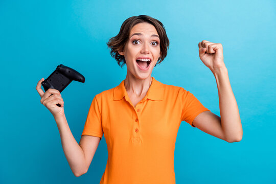 Photo of cheerful lucky girl dressed orange polo winning playstation game isolated blue color background