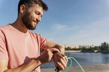 Taps the fitness watch screen and the app looks at the tracker. Interval cardio training sports man every day fitness. A confident and mentally strong man in sportswear in the park. © muse studio