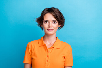 Photo of cheerful positive young girl dressed orange polo smiling isolated blue color background