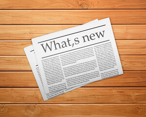 A newspaper on a wooden desk, newspaper with the headline Whats new