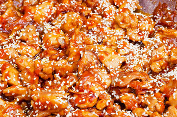 Chicken pieces fried in a sweet sauce with added sesame seeds. Background. Texture.
