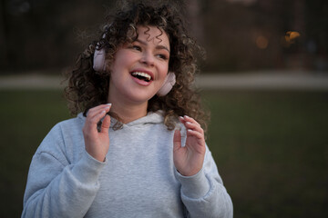 young stylish woman enjoying music in headphones, walking around the city