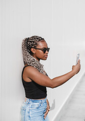 young beautiful woman with a long braids takes phone in her hands on a white background