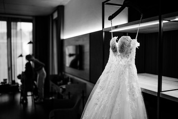 Bridal dress hanging on display in the hotel room before the wedding - obrazy, fototapety, plakaty