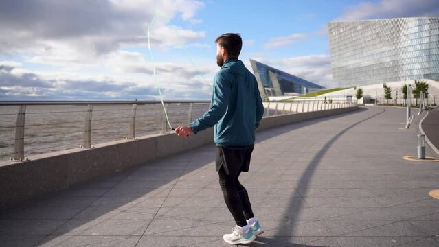 Uses a skipping rope man warm-up cardio workout jumps on the spot intense workout. Motivation a person who trains an active lifestyle. Slow motion video.