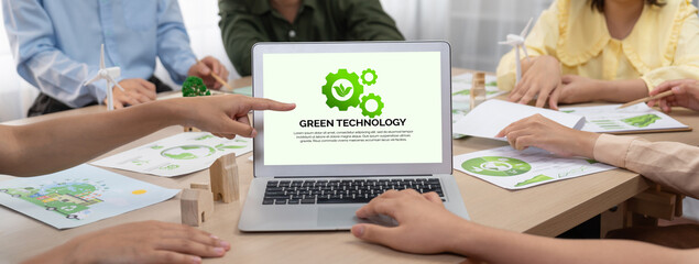 Green technology logo displayed on green business laptop while business team presenting green...