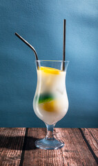 a white cocktail on a wooden table and blue background with copy space