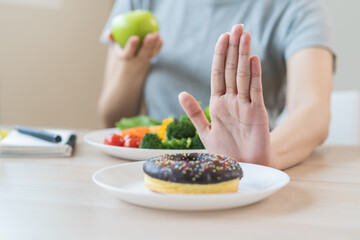 Diet, Dieting happy asian young woman, girl hand refuse, push out or deny to eat sweet donut choose green apple and salad vegetables, eat food for good health when hungry. Female weight loss person.