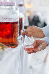 Man getting a drink at a jar filled with red juice at a wedding buffet close-up