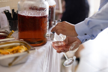 Man getting a drink at a jar filled with red juice at a wedding buffet close-up