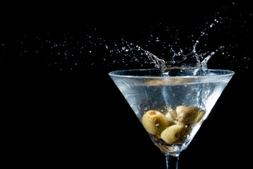 Olive splashing into a martini glass
